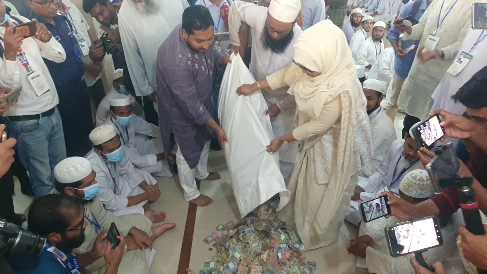 পাগলা মসজিদের দানবাক্সের টাকা গণনা করার জন্য বস্তা ঢালা হচ্ছে।